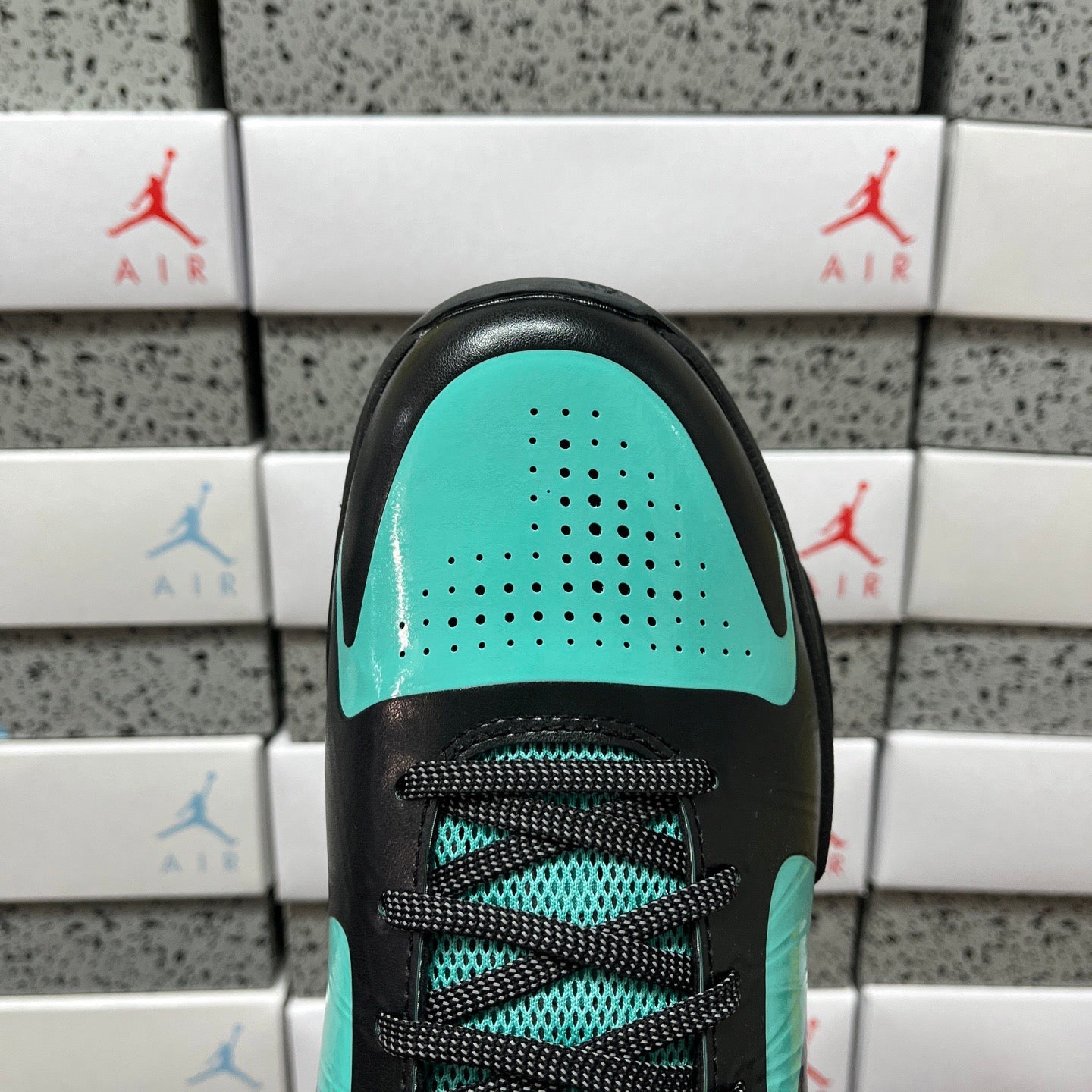Black and teal shoe tongue with teal perforated panel and teal heel accent.