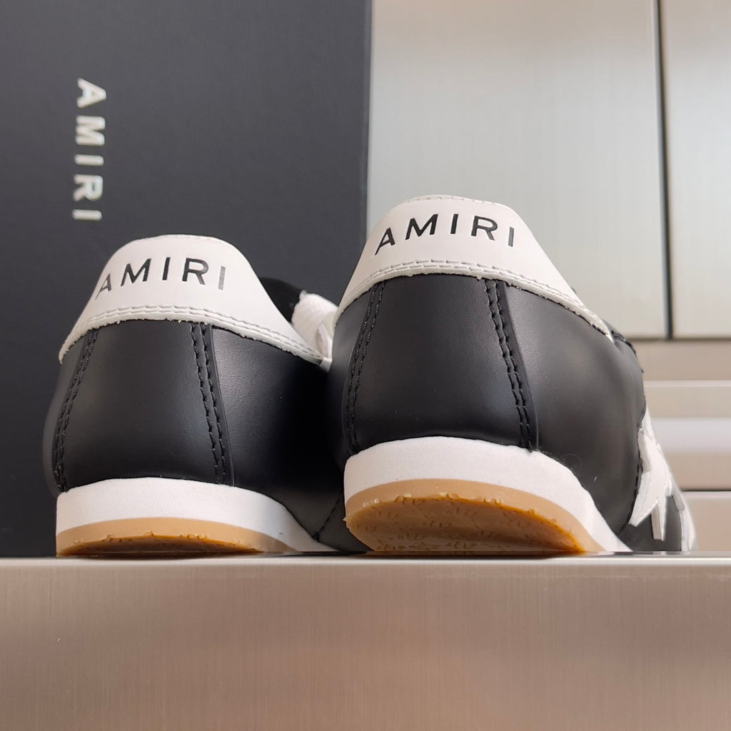 Back view of black leather sneakers with AMIRI branding on heel and gum sole