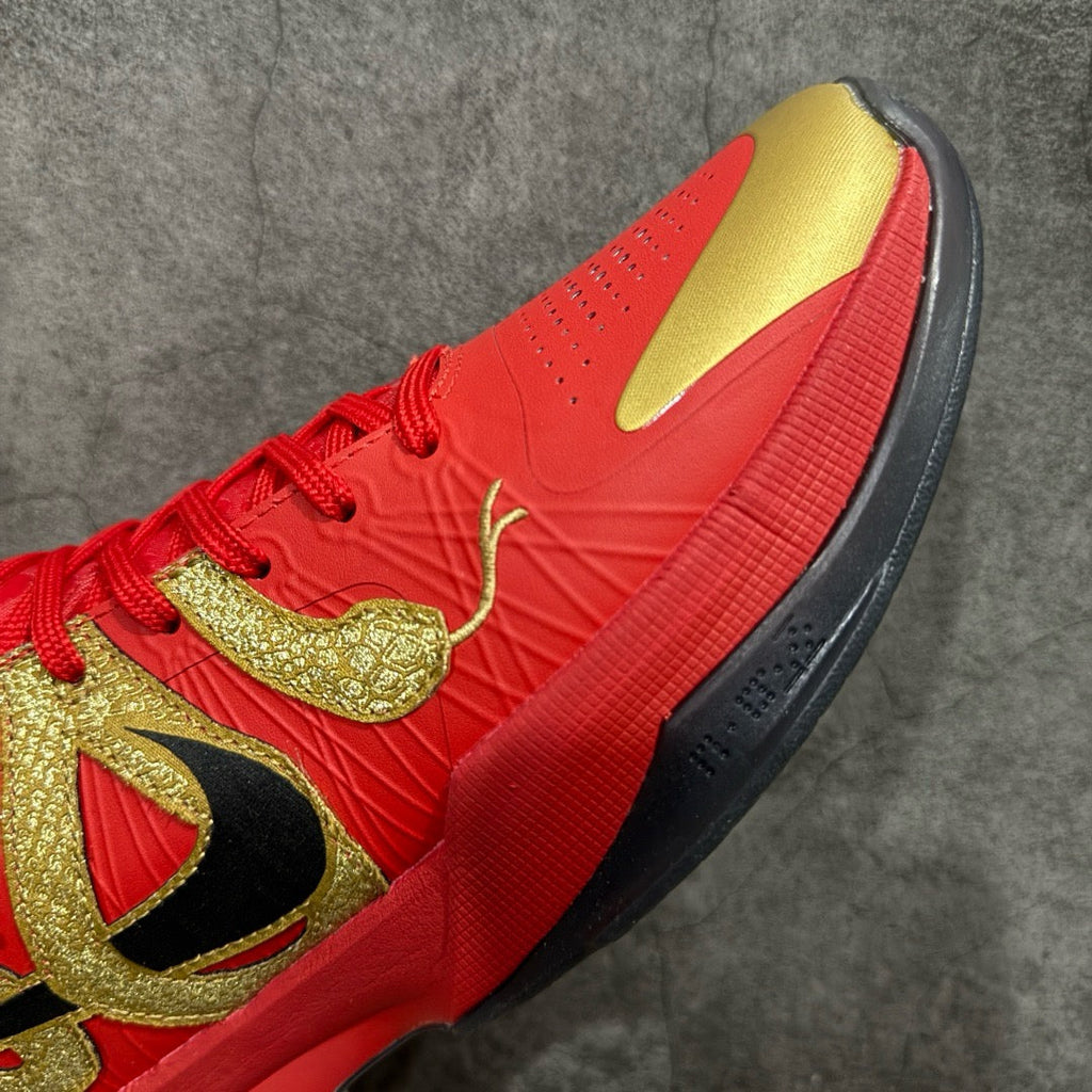 Red basketball shoe side view with gold graphics and black sole edge
