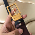 Prada belt clasp close-up: gold buckle on dark strap with burgundy edge.