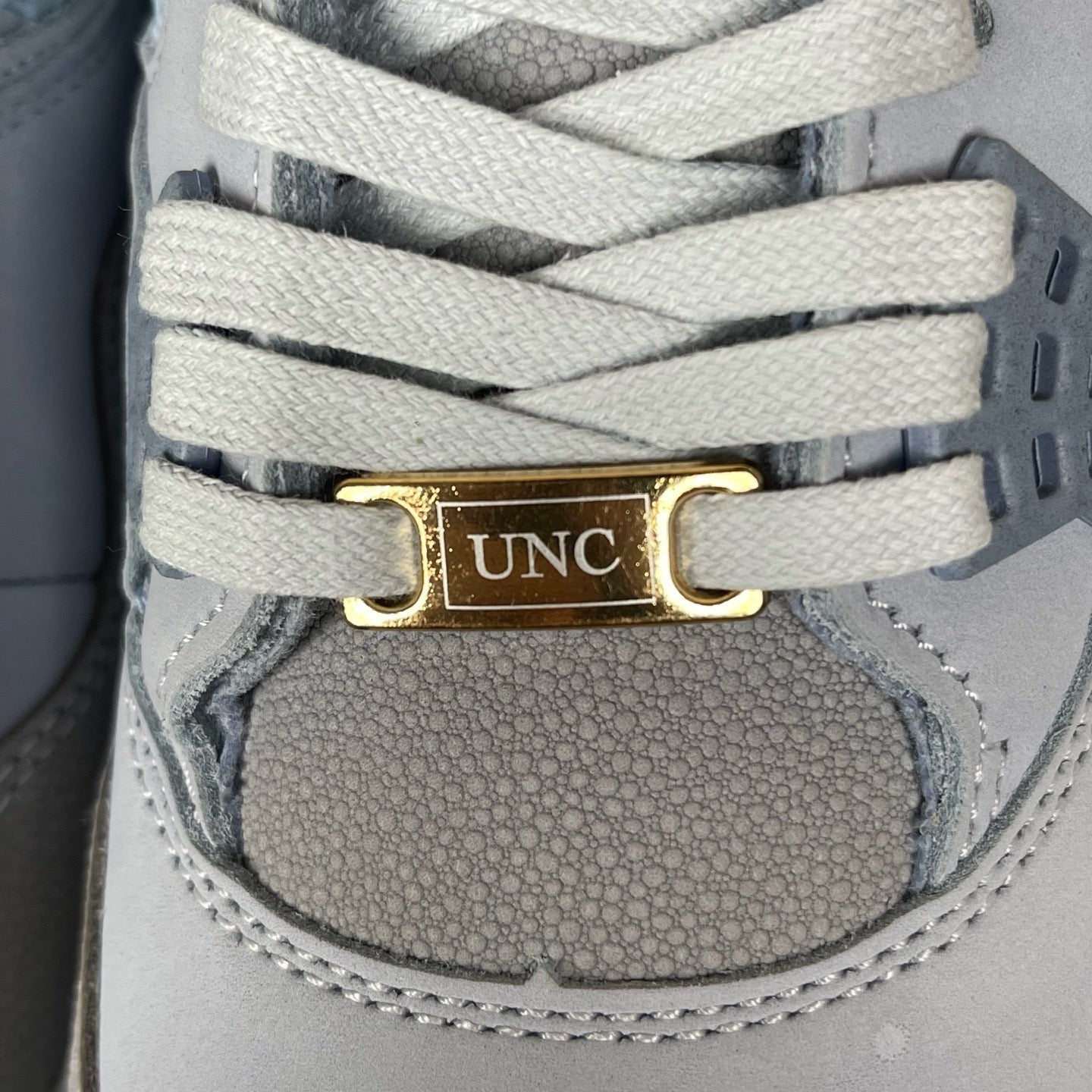 Gray sneaker lace strap with gold UNC tag and white eyelets