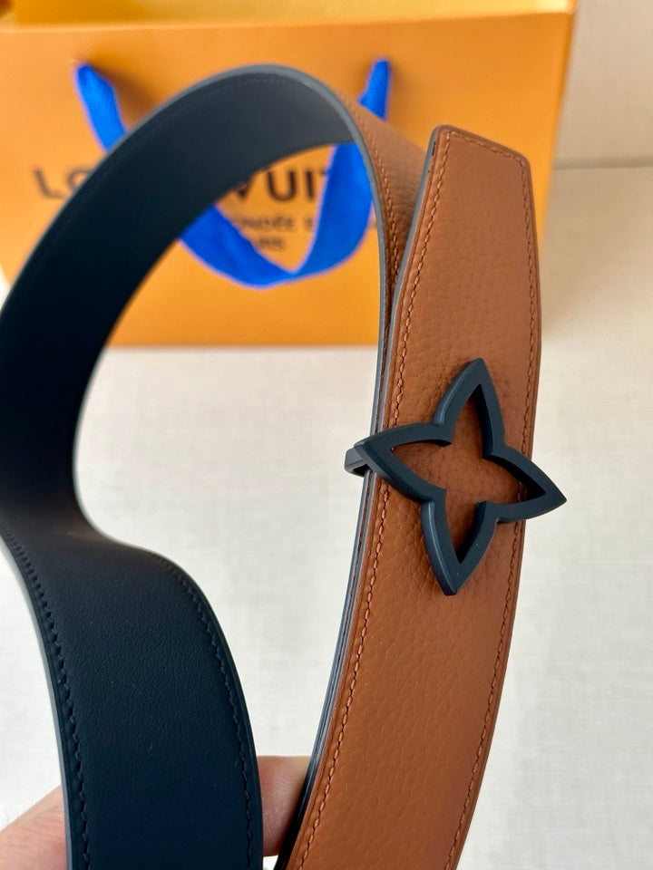 Tan leather belt with dark navy edging and large star-shaped buckle, close-up