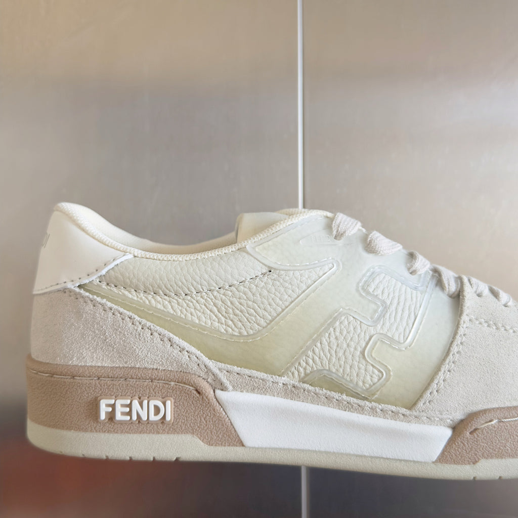 Fendi unisex sneakers close-up, white leather lace-up with beige side stripe and FENDI text.