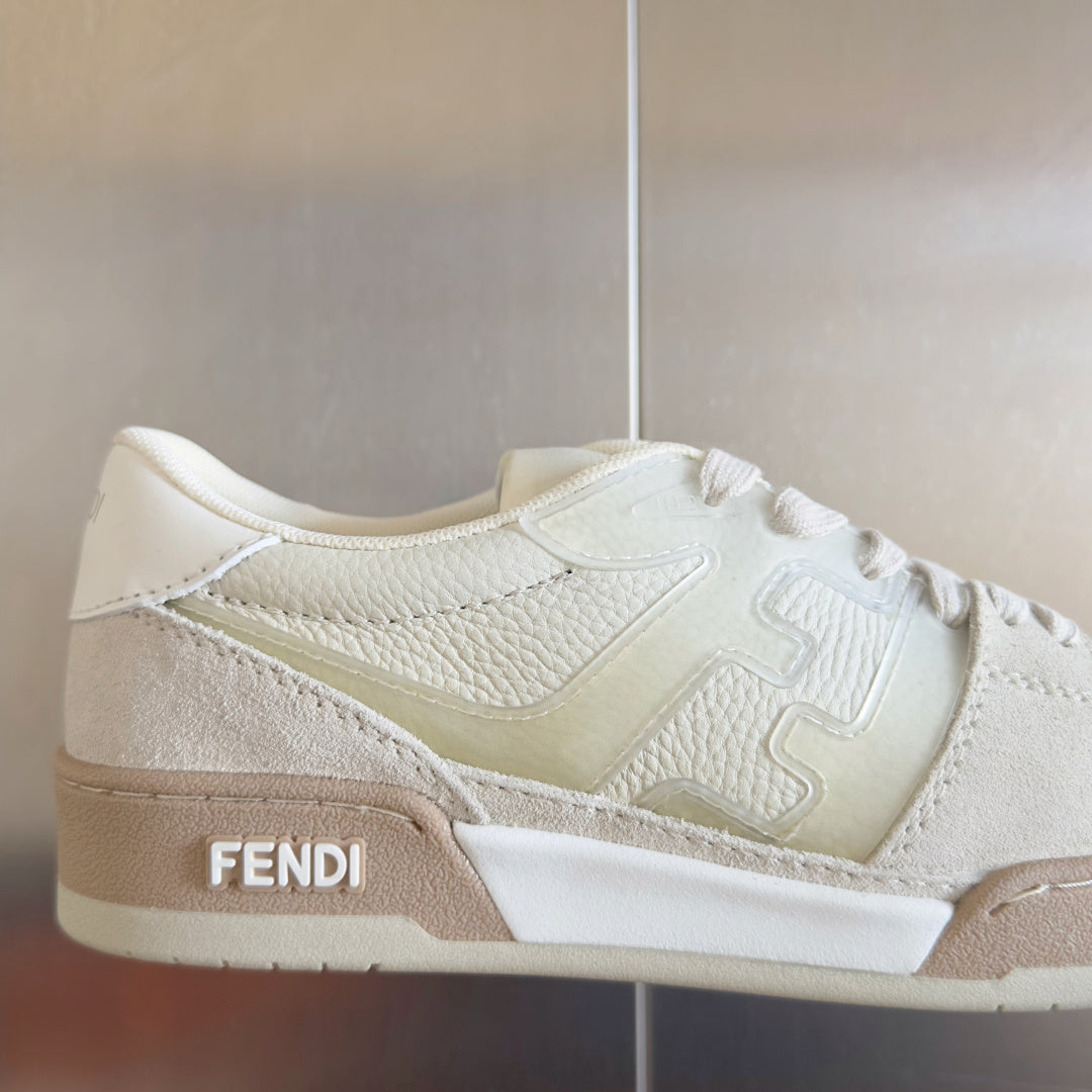 Fendi unisex sneakers close-up, white leather lace-up with beige side stripe and FENDI text.
