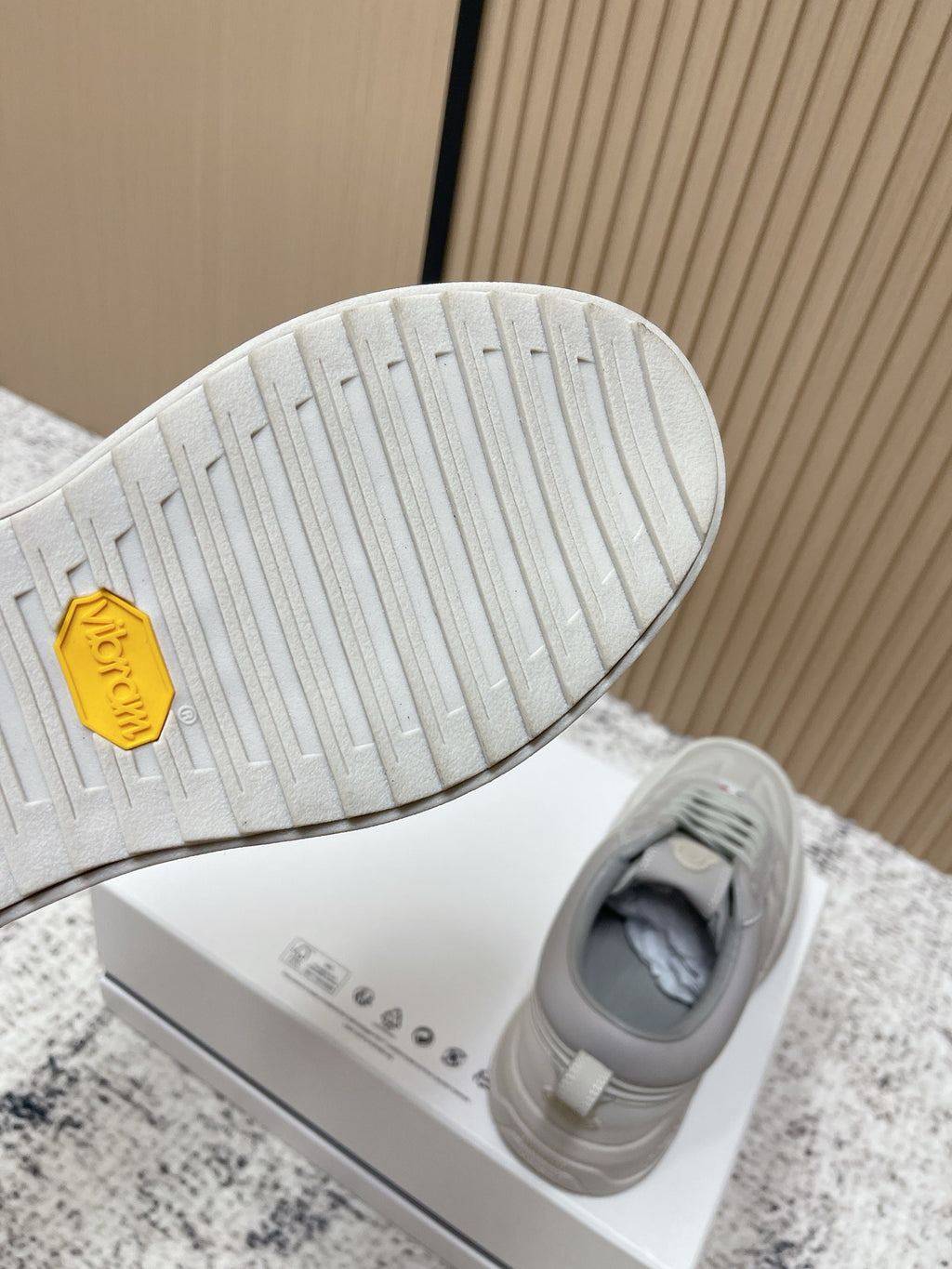 Light gray sneaker outsole with textured tread and gold Moncler hex logo