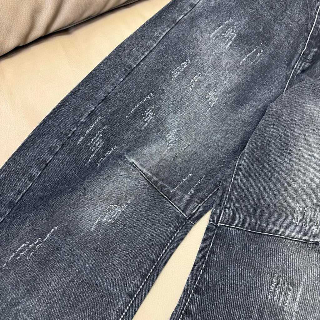 Dark wash denim jeans leg with visible distressing and stitched seams