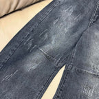 Dark wash denim jeans leg with visible distressing and stitched seams