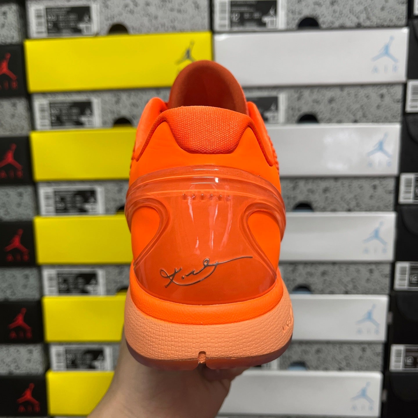 Orange sneaker rear view with cushioned collar and signature-style logo