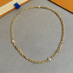 Close-up of gold-tone chain necklace with oval links and small clasp hardware.