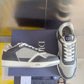 Low-top Dior sneakers with dark blue panels and white laces, side view on a box