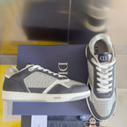 Low-top Dior sneakers with dark blue panels and white laces, side view on a box