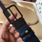 Navy belt with metal keeper and buckle hardware, textured strap close-up.
