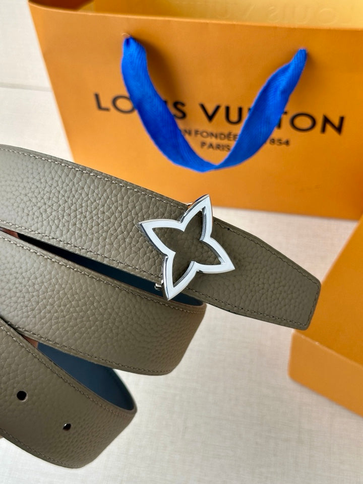 Louis Vuitton belt detail: light gray strap with silver star emblem and black inlay