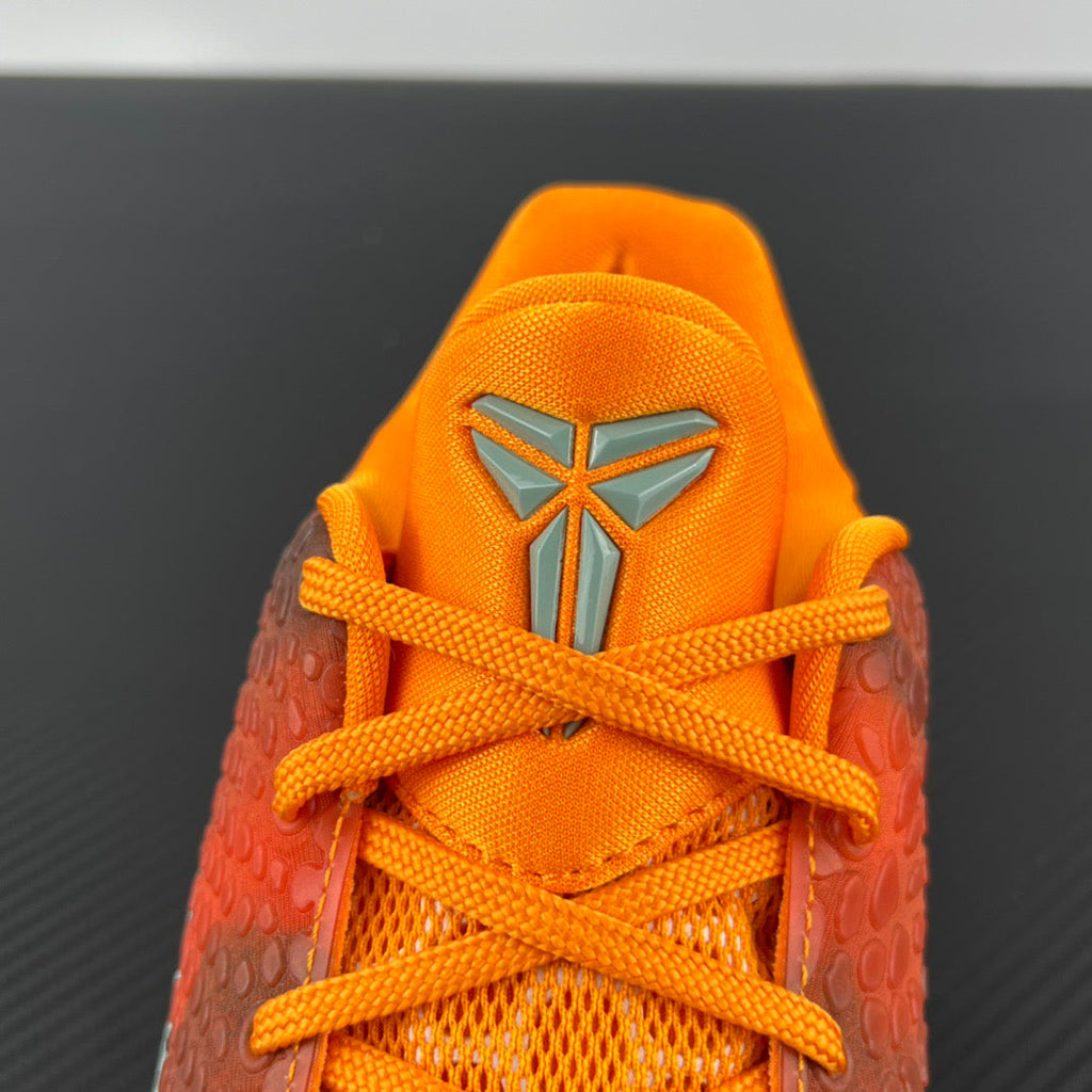 Orange lace-up athletic sneaker with gray emblem on tongue