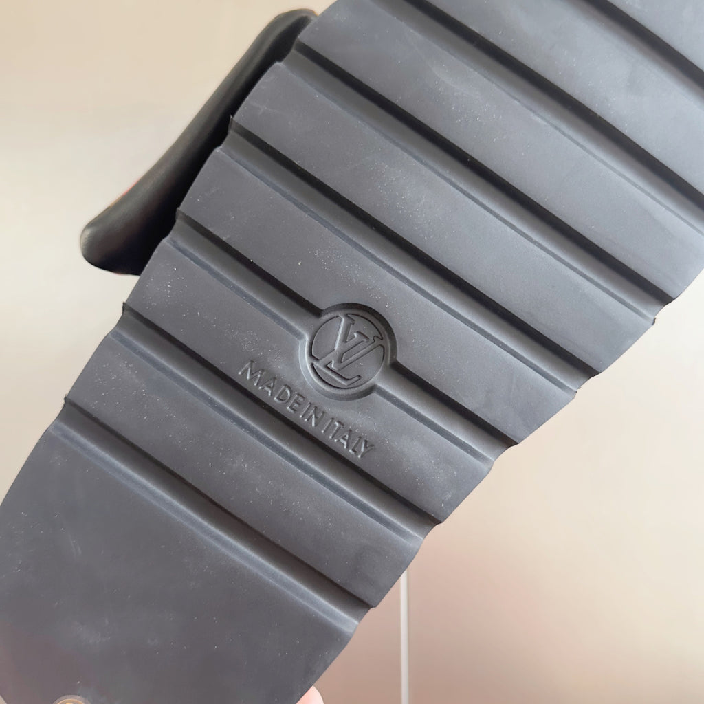 Louis Vuitton slide sandal outsole view with textured ridges and logo stamp on gray rubber