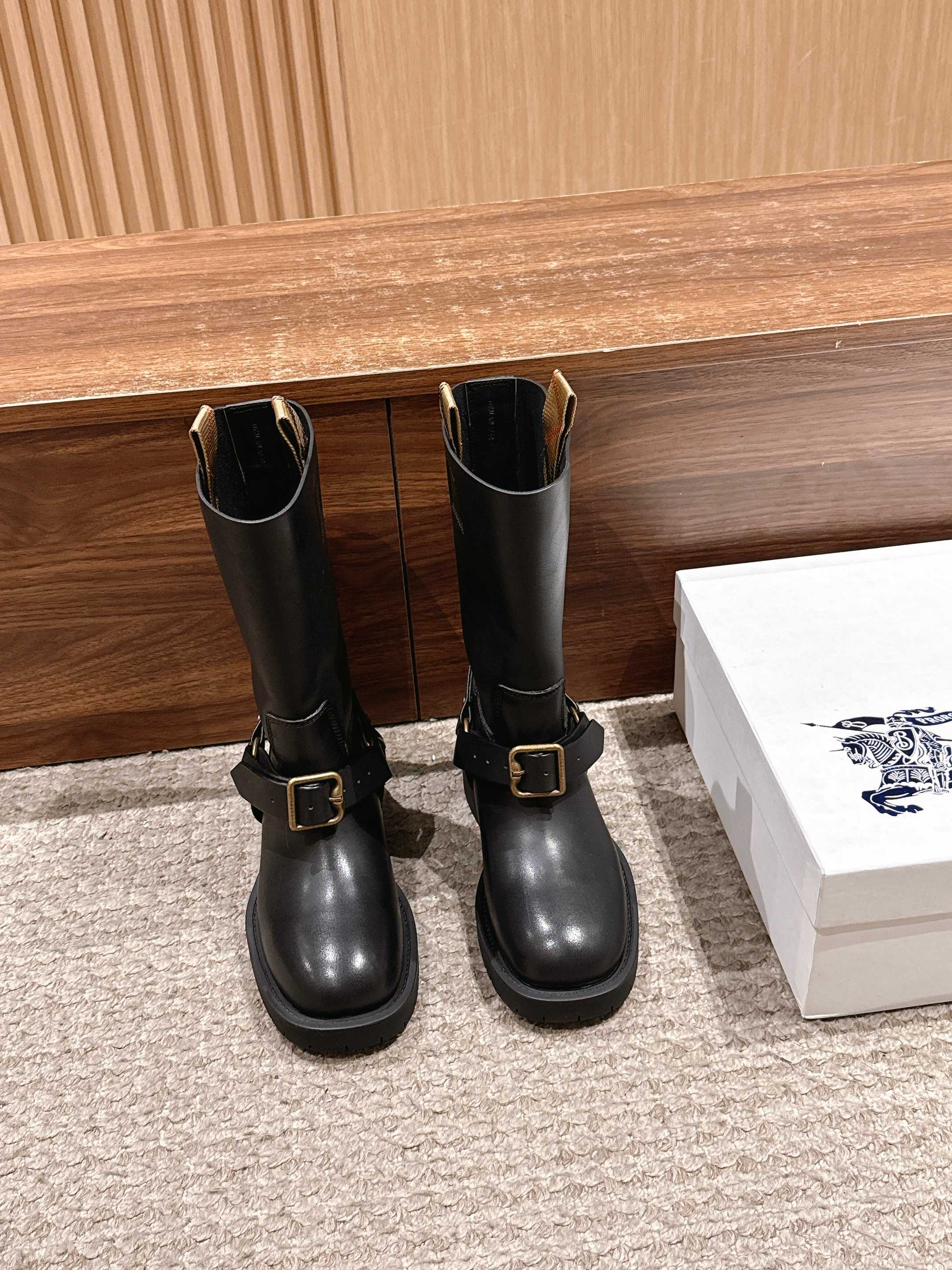 Black mid-calf leather boots with side buckle strap and low block sole.
