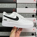 White low-top sneakers with black swoosh and Supreme label, side view