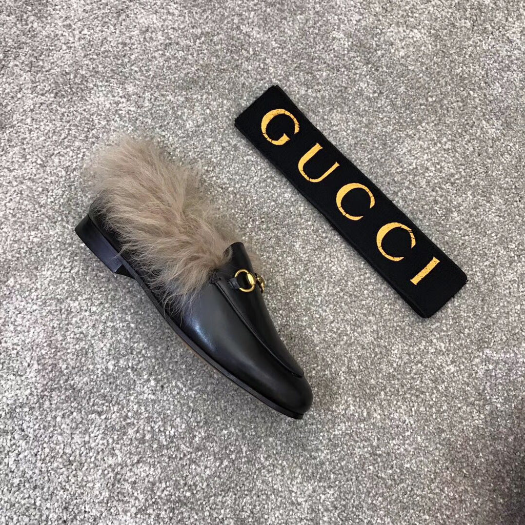 Gucci black slip-on loafer with faux fur trim and gold bit hardware, side view