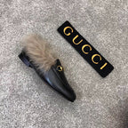 Gucci black slip-on loafer with faux fur trim and gold bit hardware, side view