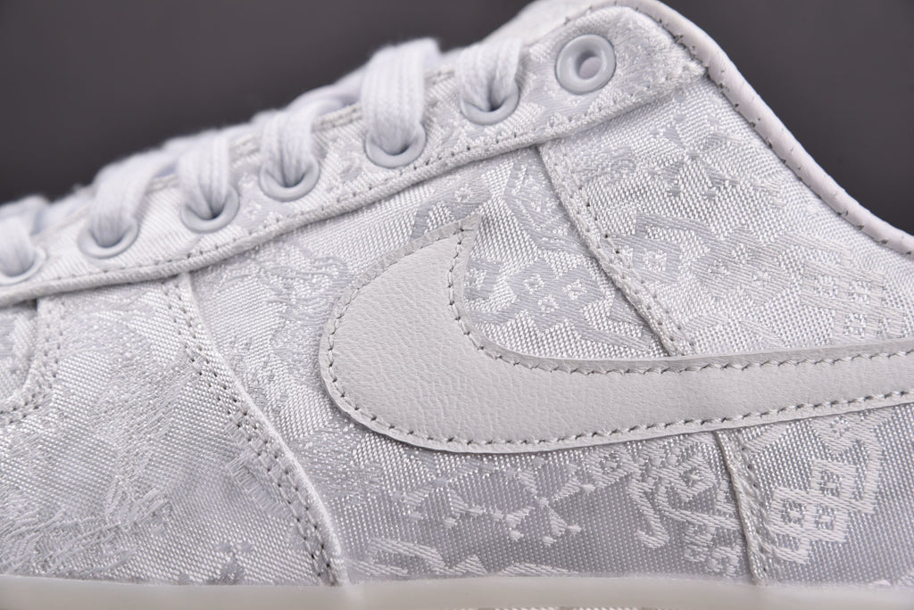 Light gray low-top sneaker with embossed monogram pattern and stitched swoosh