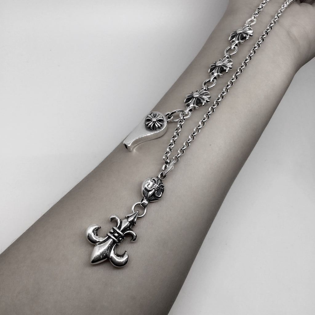 Silver chain necklace with fleur-de-lis and lock charms, worn on wrist