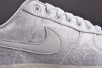Light gray low-top sneaker showing lace eyelets and embroidered swoosh
