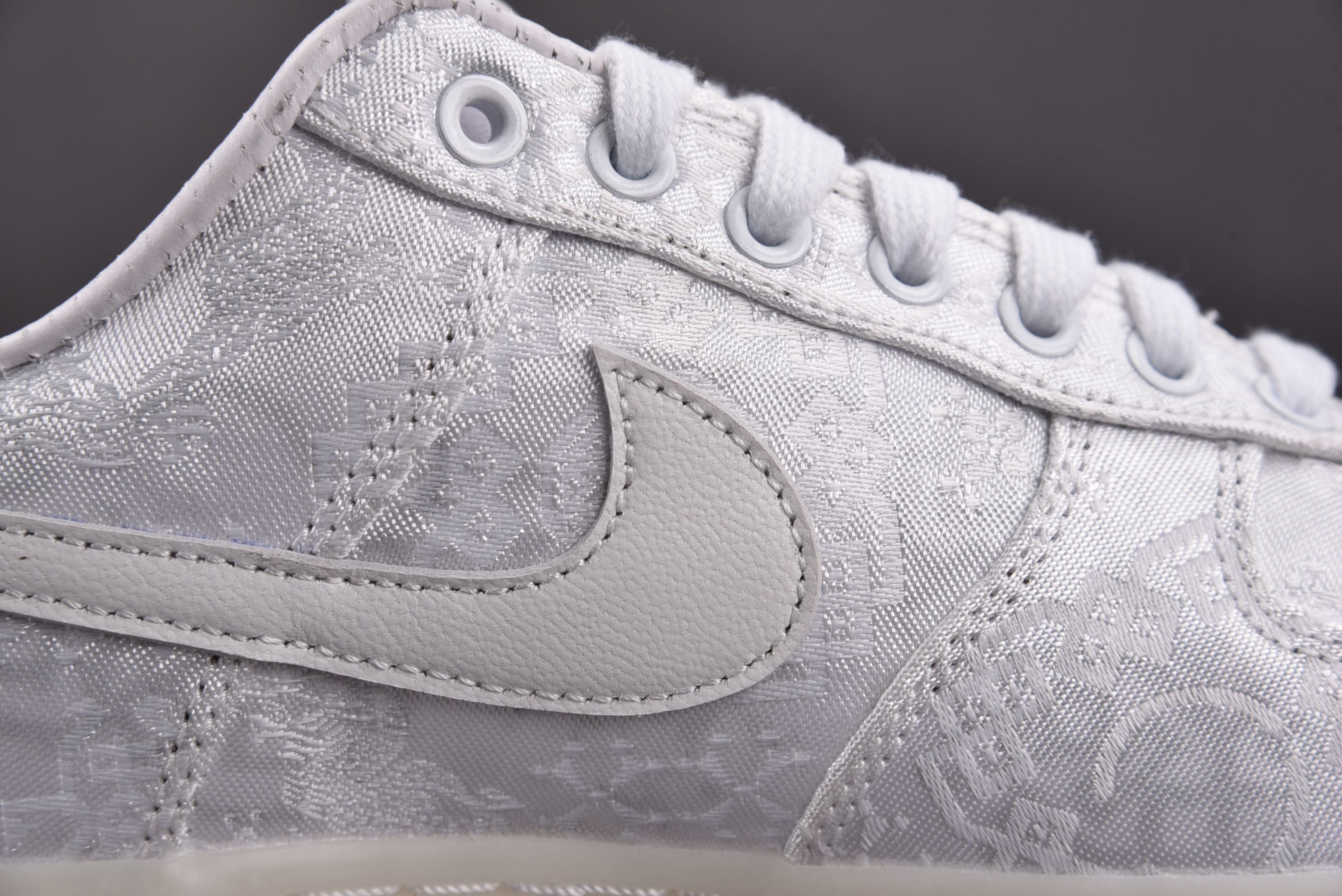Light gray low-top sneaker showing lace eyelets and embroidered swoosh