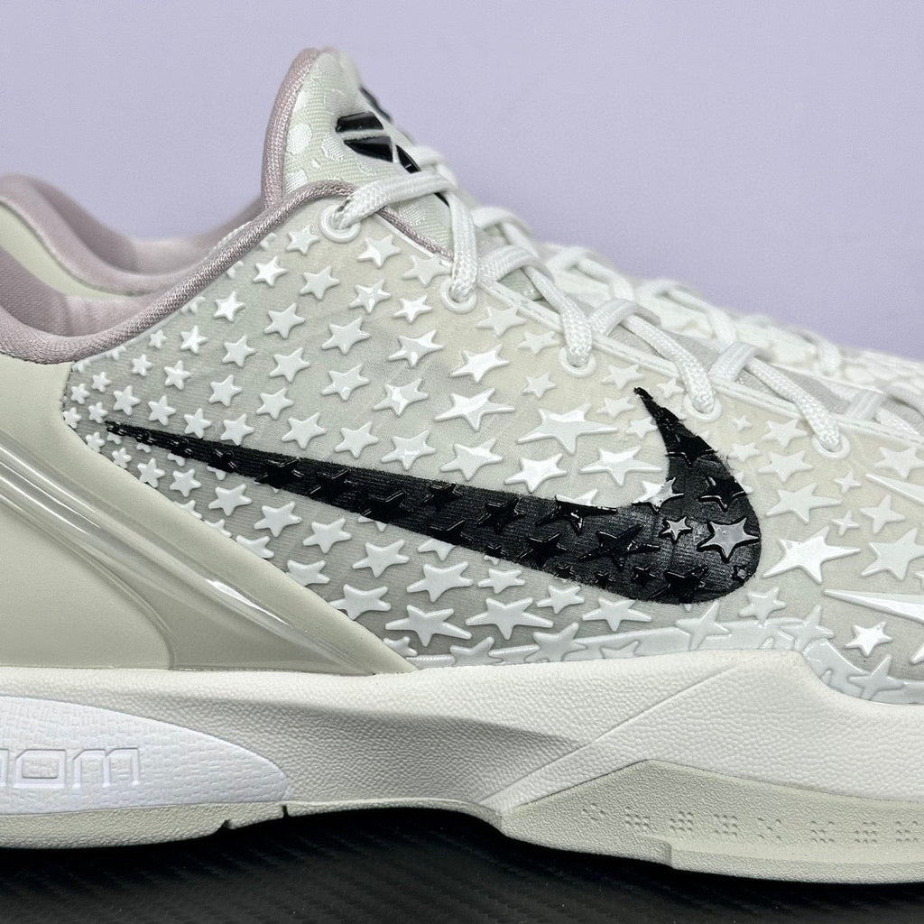 Low-top basketball sneaker close side, white star-pattern upper, black swoosh, white sole