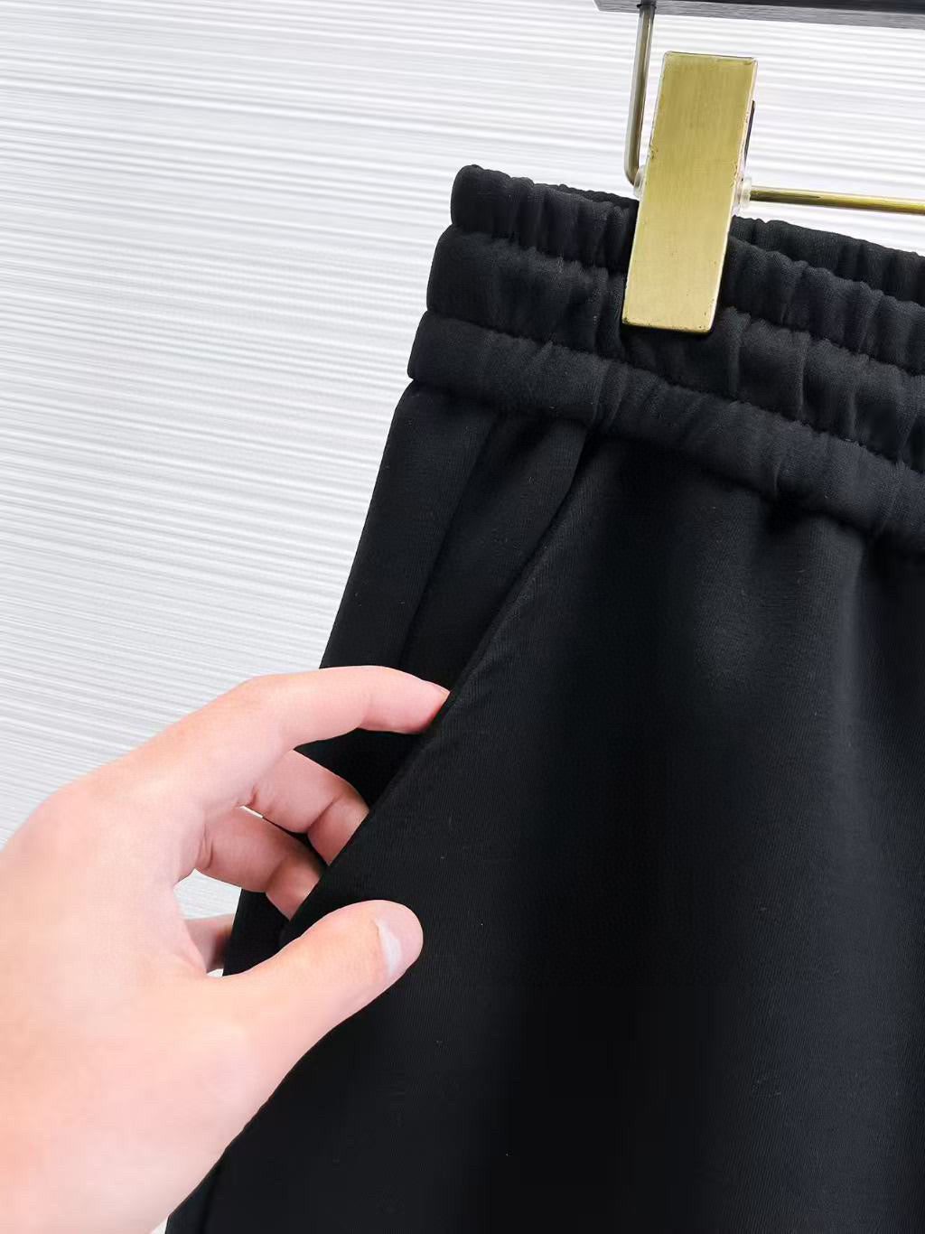 Versace black jogger pants fabric and waistband close-up, cuffed hem.
