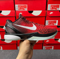 Red athletic shoe with textured upper, white swoosh, black sole, and black laces