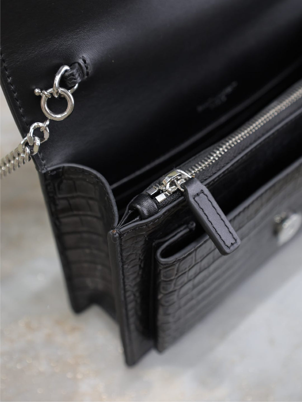 YSL croc-embossed bag detail with zipper pull, side pocket tab, black.