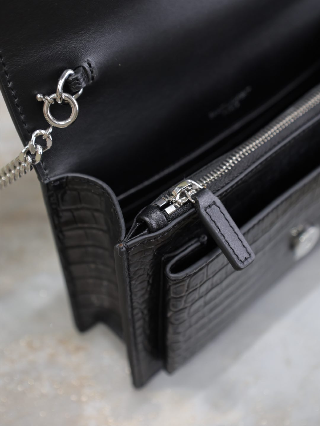 YSL croc-embossed bag detail with zipper pull, side pocket tab, black.