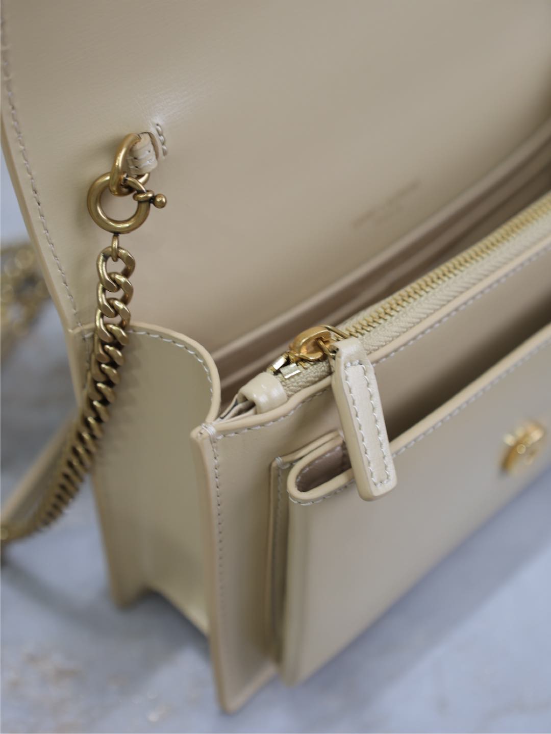 YSL cream bag interior corner with zipper pull, chain attachment, and gold hardware