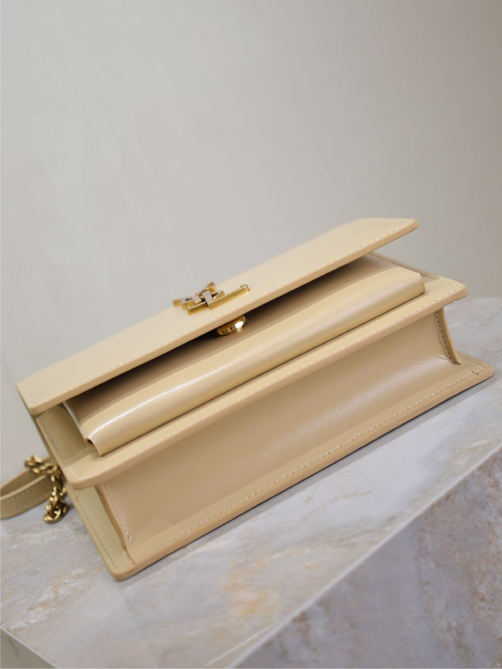 YSL cream bag viewed from top with flap open and gold-tone clasp hardware