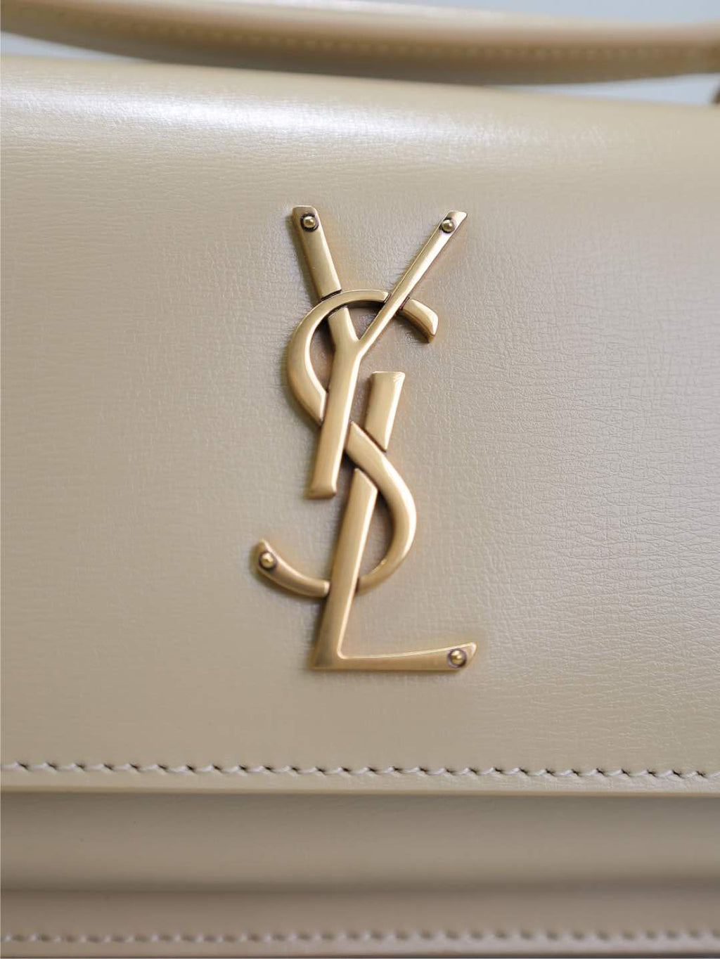 YSL cream bag with gold-tone YSL monogram logo on front panel