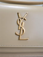 YSL cream bag with gold-tone YSL monogram logo on front panel