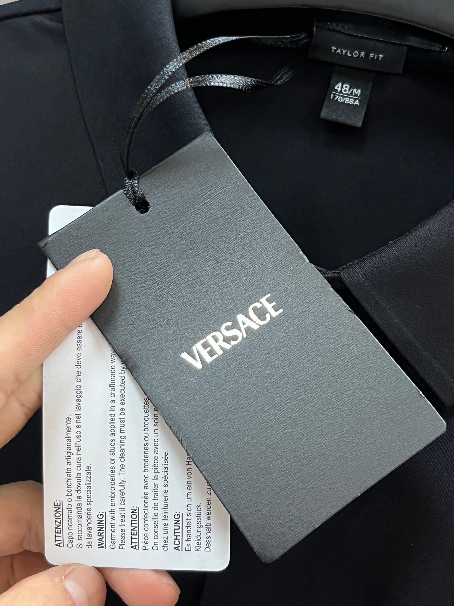 Versace clothing hang tag attached to black garment