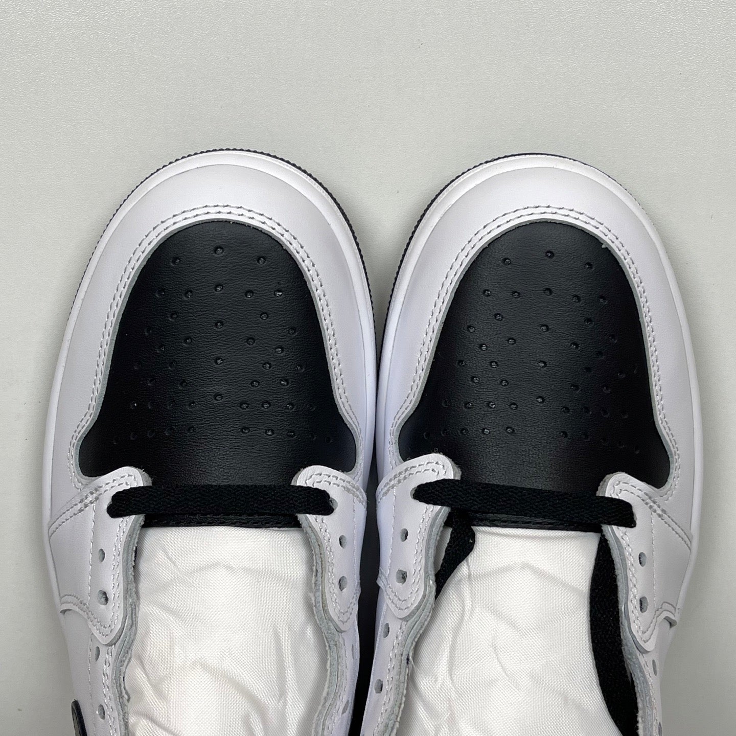 White high-top sneakers with black interior lining, lace-up eyelets, and perforated toe