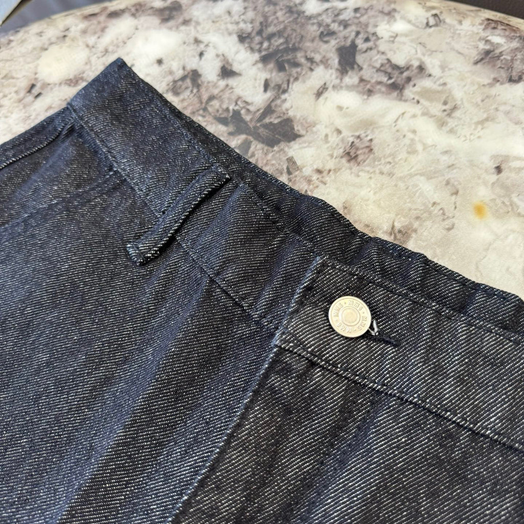 Dark denim shorts waistband detail with button and stitched fly seam