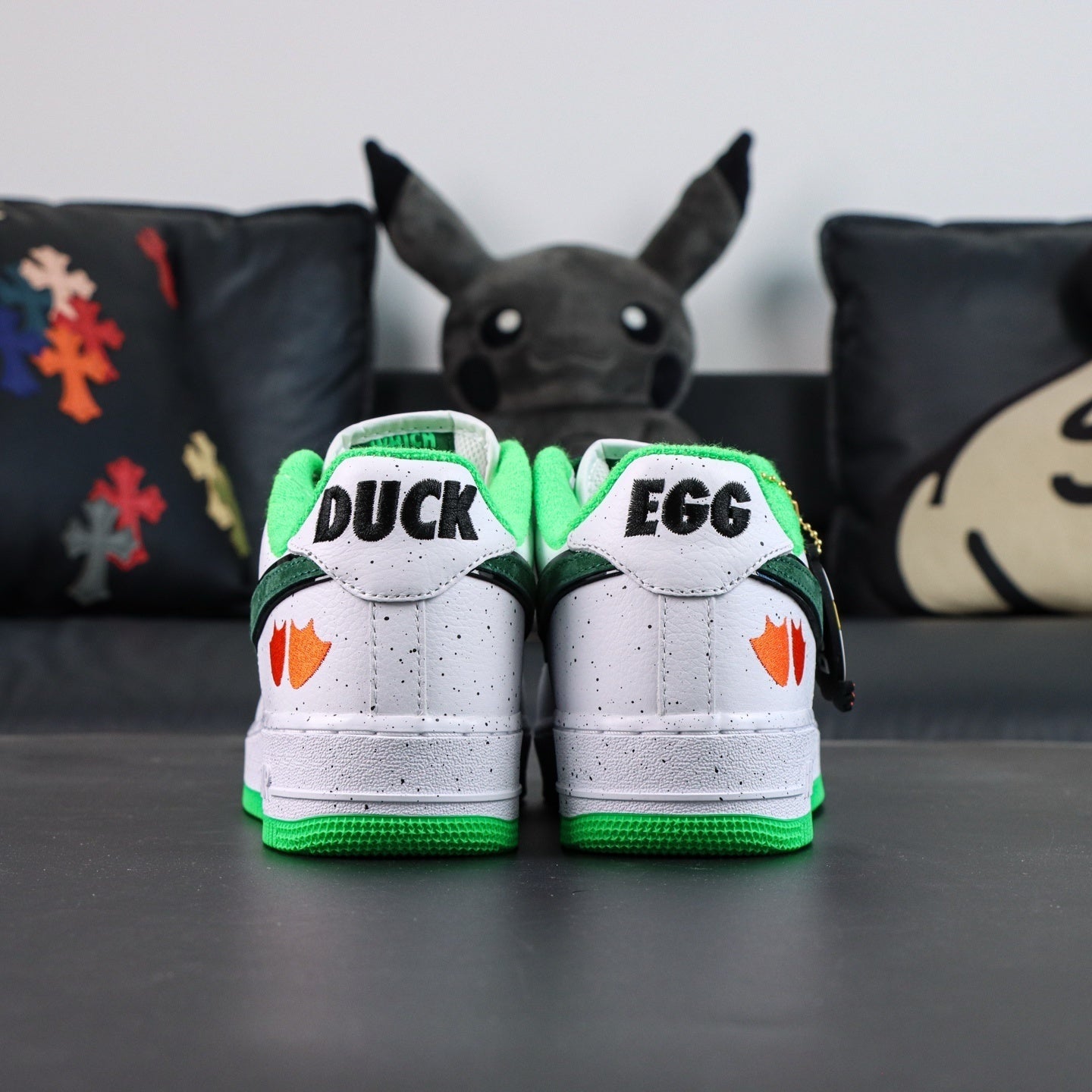 Air Force 1 sneakers, white with green accents; DUCK and EGG on rear tongues.