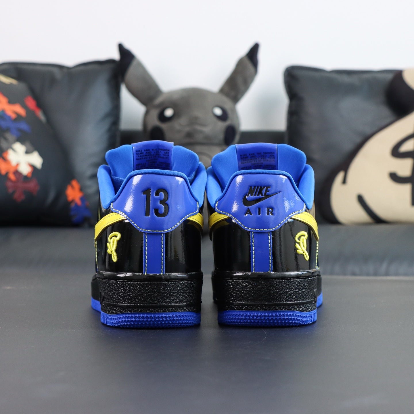 Nike Air Force 1 low-top sneakers, blue and black with yellow accents; back view, Air heel.