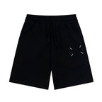 Black Maison Margiela shorts with elastic waist, drawstring, and dash line graphic.