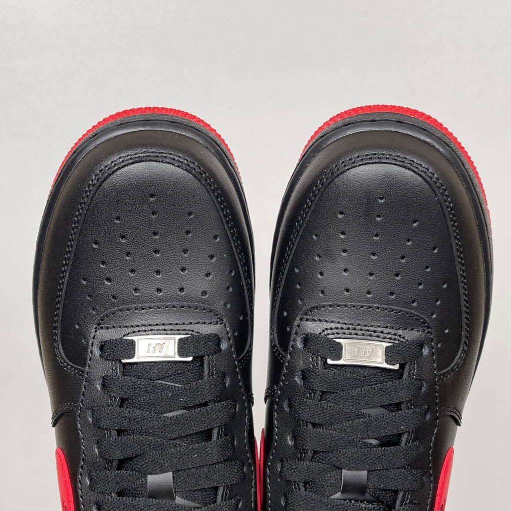 Black low-top sneakers with black laces and perforated toe panels