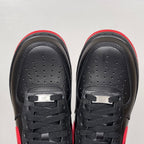 Black low-top sneakers with black laces and perforated toe panels