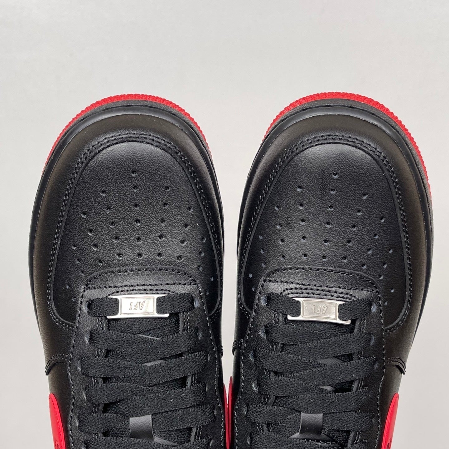 Black low-top sneakers with black laces and perforated toe panels