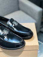 Pair of black leather loafer shoes, close-up on metal buckle detail