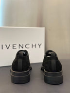 Black lace-up shoes shown from heel with elastic tabs and rubber outsole.