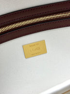 Close-up of gold 'FENDI' brand label on white fabric with maroon leather edge