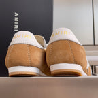 Tan suede sneakers with white heel tabs showing AMIRI branding