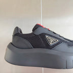 Prada unisex sneaker, close side view: dark gray mesh with overlays and red lace tab
